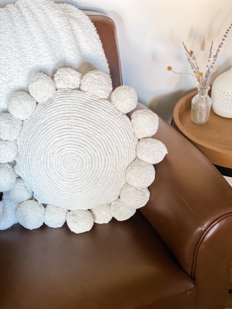 Round pillow sitting on a brown leather chair
