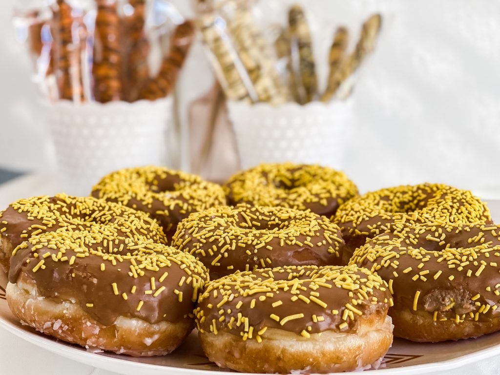 maple donuts with yellow sprinkles sitting on a tray 