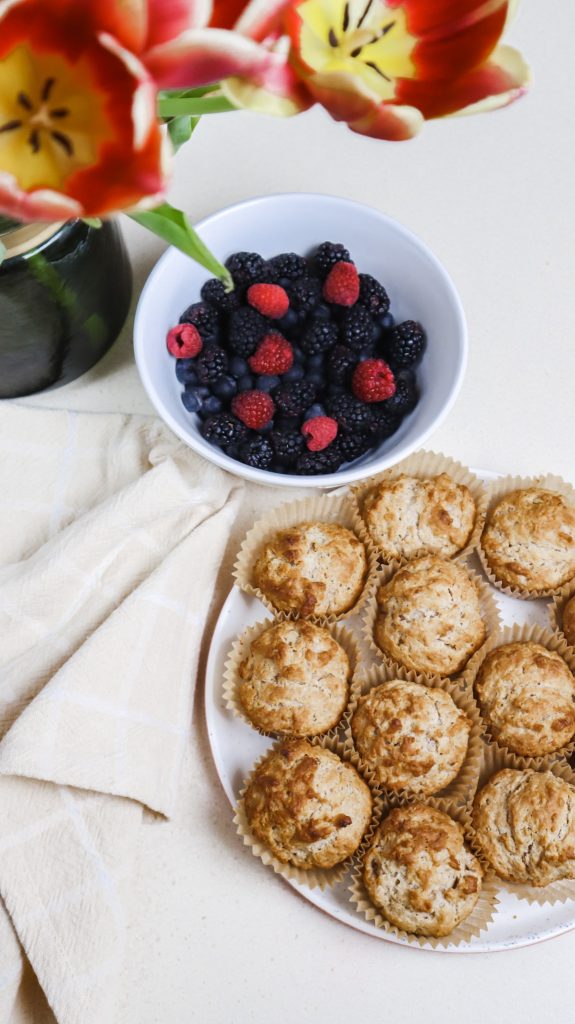 Cinnamon Breakfast Biscuits on a plate next to a bowl full of berries and tulips in a vase