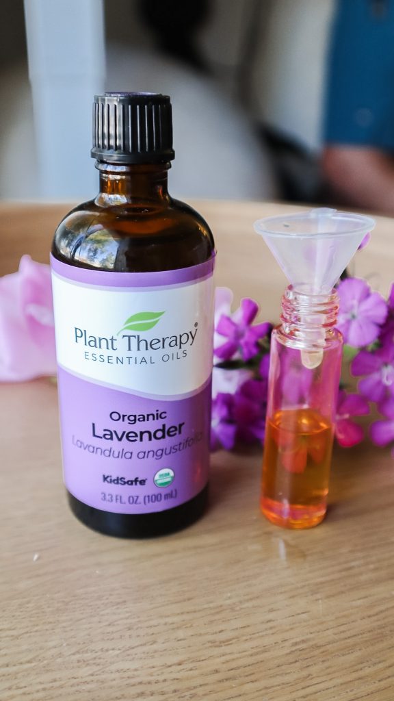 A bottle of lavender essential oil next to a roller bottle sitting on a table