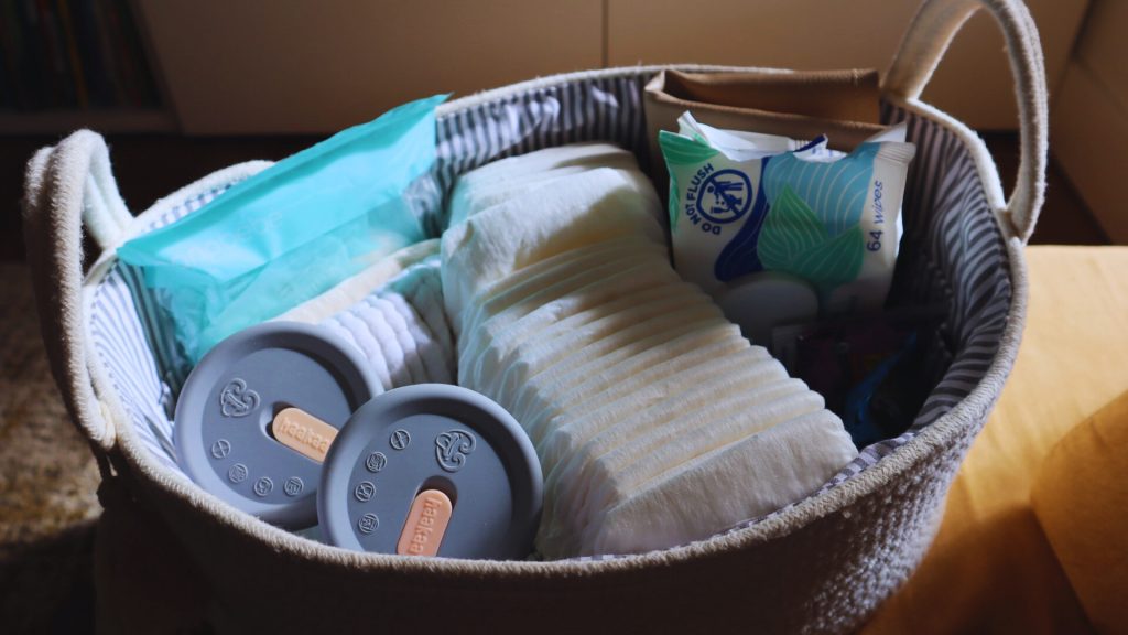 A basket of diapers and wipes to prepare for a happy postpartum experience